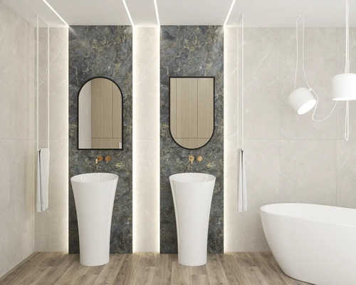 Modernes Badezimmer mit zwei weißen Säulenwaschbecken vor dunklen Marmorfliesen, zwei Spiegeln, goldfarbenen Armaturen und freistehender Badewanne.
