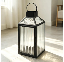 Schwarze Metalllaterne mit geriffelten Glaspaneelen und einem halbrunden Tragegriff, stehend auf einem hellen Fliesenboden.