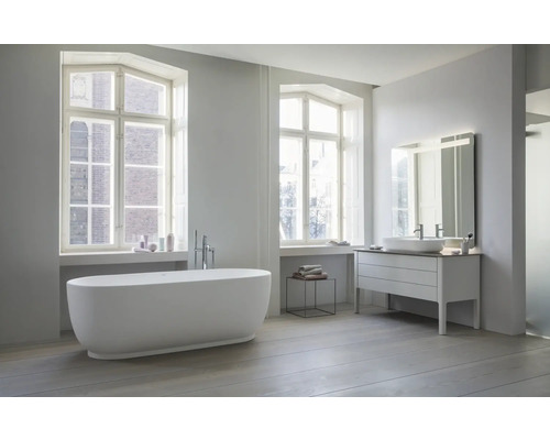 Modernes helles Badezimmer mit freistehender Badewanne bodenstehender Armatur Waschtisch mit Aufsatzbecken und großem beleuchtetem Spiegel