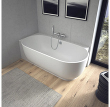 Moderne ovale freistehende Badewanne in einem hellen Badezimmer mit Holzfußboden und Betonoptik-Wänden.