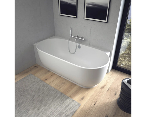 Moderne ovale freistehende Badewanne in einem hellen Badezimmer mit Holzfußboden und Betonoptik-Wänden.
