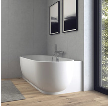 Moderne, ovale Badewanne in Weiß mit Wandarmatur aus Chrom in einem hellen Badezimmer mit Betonoptik-Wänden und Holzparkett.