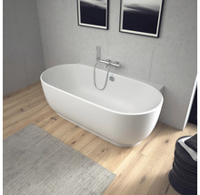 Freistehende ovale Badewanne mit wandmontierter Chrom-Armatur in einem modernen Badezimmer mit Holzboden und Wänden in Betonoptik.