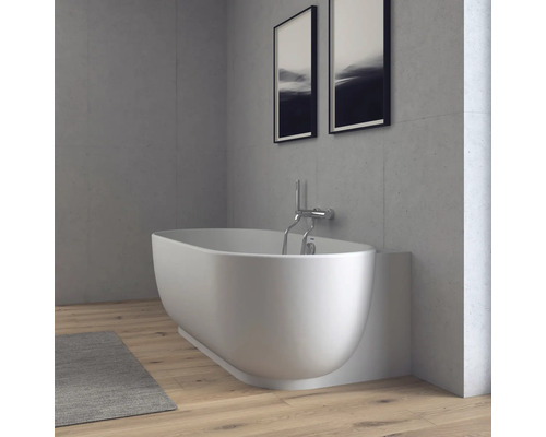 Modernes Badezimmer mit Badewanne, Wandarmatur, Wänden in Betonoptik und Holzboden in einer hellen, minimalistischen Atmosphäre.