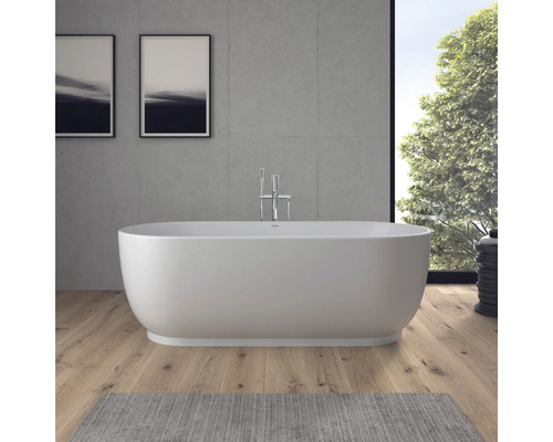 Freistehende Badewanne in einem modernen Badezimmer mit Holzboden, Sichtbetonwand und verchromter Standarmatur.