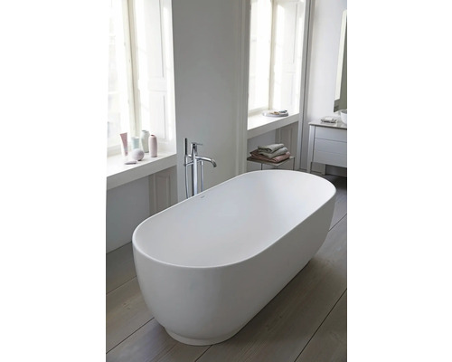 Freistehende ovale Badewanne in einem hellen modernen Badezimmer mit bodenstehender Armatur und Holzfußboden.