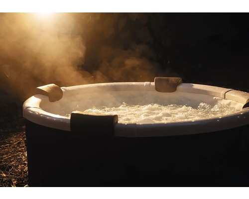 Runder aufblasbarer Whirlpool mit sprudelndem Wasser, Kopfstützen und aufsteigendem Dampf im Außenbereich bei Nacht.