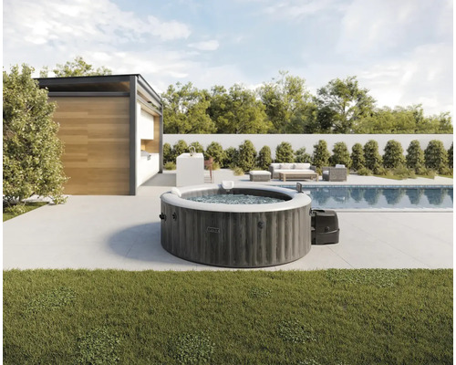 Intex runder aufblasbarer Whirlpool in Holzoptik auf einer modernen Terrasse neben einem Pool und Gartenhaus.