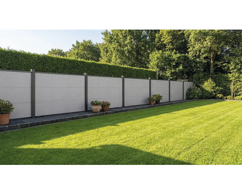 Moderner Sichtschutzzaun aus grauen Faserzementplatten mit dunklen Metallpfosten in einem gepflegten Garten mit Rasen und Hecke.