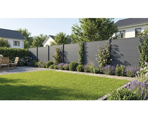 Moderner Sichtschutzzaun in Anthrazit in einem Garten mit Rasen, Lavendel und Holzmöbeln auf einer Kiesterrasse.