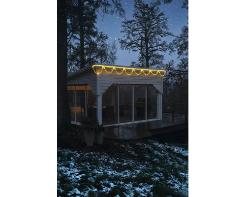 LED-Eisregen-Lichterkette warmweiß an einem modernen Gartenhaus in winterlicher Umgebung bei Nacht.
