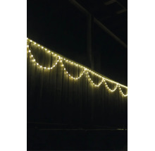 LED-Lichterkette warmweiß an einem Holzzaun im Außenbereich bei Nacht.