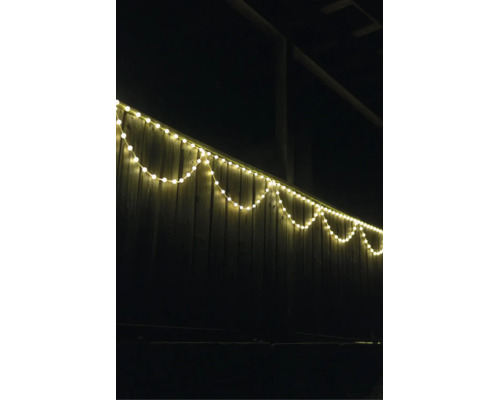 LED-Lichterkette warmweiß an einem Holzzaun im Außenbereich bei Nacht.