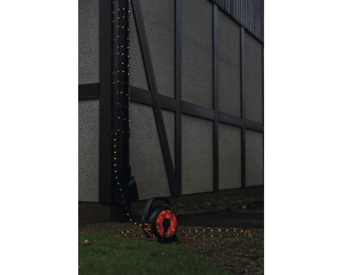 LED-Lichterkette auf Kabeltrommel für den Außenbereich, um ein Fallrohr an einer Hauswand gewickelt.