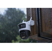 Wetterfeste Überwachungskamera mit zwei Objektiven an einer Holzwand im Regen montiert.