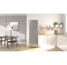 Moderne helle Küche mit einem hohen silbernen Kühlschrank neben weißen Schränken mit Holzoberfläche und einem Essbereich mit Holztisch.