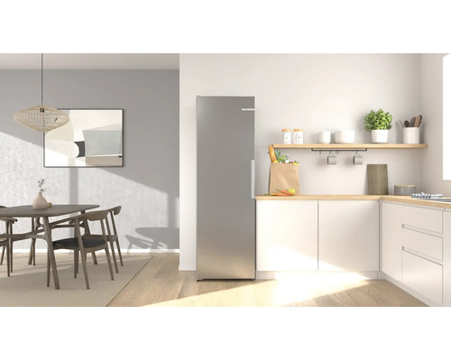 Moderne, helle Küche mit freistehendem Edelstahl-Kühlschrank, weißen Schränken mit Holz-Arbeitsplatte und einem angrenzenden Essbereich.