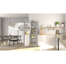 Helle, moderne Küche mit einem hohen, offenen silbernen Kühlschrank voller Lebensmittel neben einer hellen Holz-Arbeitsplatte.