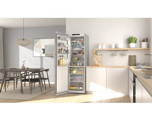 Helle, moderne Küche mit einem hohen, offenen silbernen Kühlschrank voller Lebensmittel neben einer hellen Holz-Arbeitsplatte.