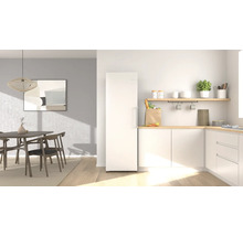 Helle, moderne Küche mit einem freistehenden weißen Kühlschrank, Arbeitsplatten aus hellem Holz und einem angrenzenden Essbereich.