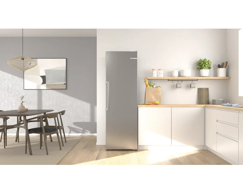 Moderner Kühlschrank aus Edelstahl in einer hellen, aufgeräumten Küche mit Essbereich, Holzmöbeln und weißen Schränken.