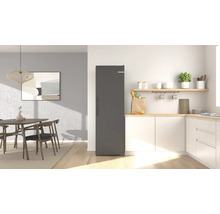 Moderner, heller Küchenbereich mit freistehendem Kühlschrank, Schränken, einer Holzarbeitsplatte und einem Essbereich mit Tisch.