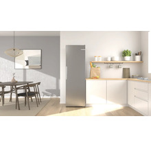 Moderner freistehender Kühlschrank in Edelstahloptik in einer hellen, organisierten Küche mit Essbereich und Holzelementen.