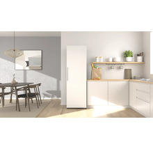 Helle, moderne Küche mit freistehendem weißem Kühlschrank, hölzernen Arbeitsplatten, weißen Schränken und Essbereich mit Holzmöbeln.