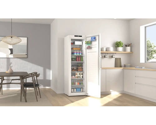 Weißer Gefrierschrank mit geöffneter Tür in einer hellen, modernen Küche mit Essbereich und übersichtlich eingeräumten Lebensmitteln.