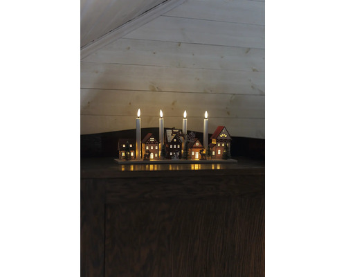 Weihnachtsleuchter aus Holz mit vier LED-Kerzen, beleuchteten Miniaturhäusern, Tannenbäumen und Rentierschlitten.