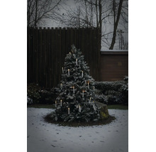 Verschneiter Weihnachtsbaum im Außenbereich mit leuchtenden kabellosen LED Kerzen in einem winterlichen Garten.