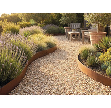 Gartenweg aus Kies mit geschwungener Beetbegrenzung aus Metall in Edelrost-Optik, bepflanzt mit Lavendel, Ziergräsern und Sukkulenten.