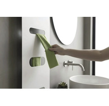 Hand entnimmt ein grünes Handtuch aus einem weißen Design-Heizkörper in einem modernen Badezimmer mit Waschbecken und Armatur.