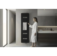 Modernes Badezimmer mit schwarzem Design Heizkörper an der Wand, einer Frau im weißen Bademantel und einem Waschtisch mit dunklem Unterschrank.