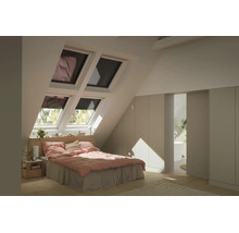 Helles Schlafzimmer im Dachgeschoss mit vier Dachfenstern, Bett mit rosa Bettwäsche, Einbauschränken und Blick in das angrenzende Badezimmer.