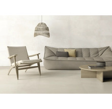 Helles, modern eingerichtetes Wohnzimmer mit großformatigen Fliesen, grauem Sofa, Holz-Sessel mit Geflecht und gewebter Pendelleuchte.