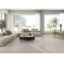Helles, geräumiges Wohn- und Esszimmer mit hellen Bodenfliesen im Großformat, modularem Sofa und großen Fensterfronten.