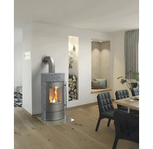 Moderner Kaminofen mit Natursteinverkleidung in hellem, geräumigem Wohnzimmer mit Holzboden, Esstisch und integriertem Holzregal in der Wand.