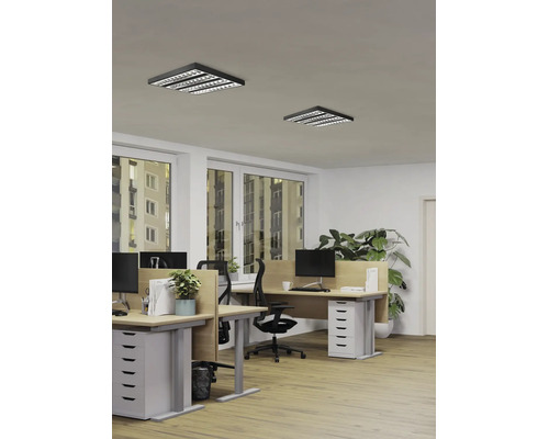 Modernes Büro mit zwei quadratischen schwarzen LED-Rasterdeckenleuchten, Holztischen und ergonomischen Stühlen in einem hellen Arbeitsraum.