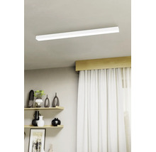 Moderne LED-Deckenleuchte in flacher, rechteckiger Form montiert an einer hellen Decke in einem hellen Wohnzimmer mit Regalen und Vorhängen.