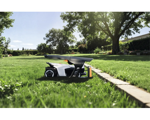 Mähroboter unter einer Garagenabdeckung auf einer Rasenfläche in einem sonnigen Garten mit Bäumen und Steineinfassung.