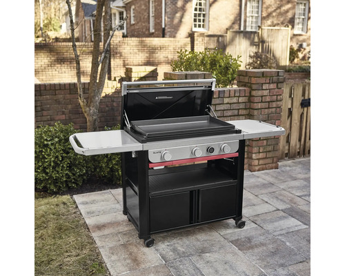 Weber Slate Gasgrill mit drei Brennern, Deckel und Seitenablagen auf einer gepflasterten Terrasse.