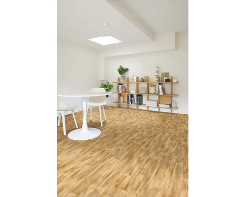 Helles Zimmer mit modernem Bodenbelag in Holzoptik, weißem Rundtisch, Stühlen und einem Holzregal an der Wand.