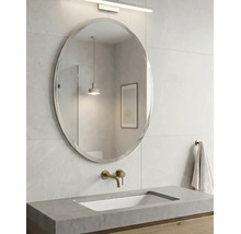 Moderner Badezimmerbereich mit einem ovalen Wandspiegel, einem Waschtisch aus Beton mit eingebautem Becken und einer Wandarmatur.