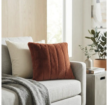 Dekokissen mit weicher Rippenstruktur in Terracotta auf einem hellgrauen Sofa in einem hellen Wohnzimmer.
