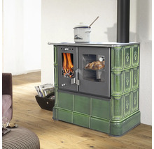 Grüner Kachelherd mit Sichtfenster für Feuer und Backofen in einem hellen Wohnraum mit Holzboden.