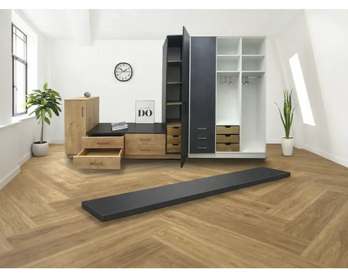 Modulares Kleiderschranksystem in Holzoptik und Schwarz mit Schubladen und Regalen in einem hellen Raum mit Fischgrät-Bodenbelag.