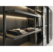 Moderner begehbarer Kleiderschrank mit dunklen Holzregalen, integrierter LED-Beleuchtung und Glasschiebetüren.