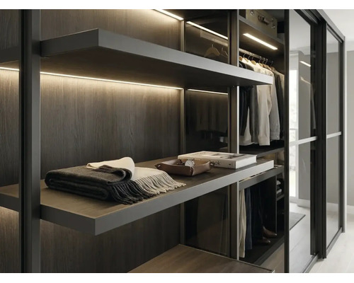 Moderner begehbarer Kleiderschrank mit dunklen Holzregalen, integrierter LED-Beleuchtung und Glasschiebetüren.
