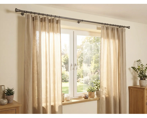 Helle Szene mit einer dunklen Vorhangstange aus Metall über einem Fenster, beigen halbtransparenten Vorhängen und Zimmerpflanzen.